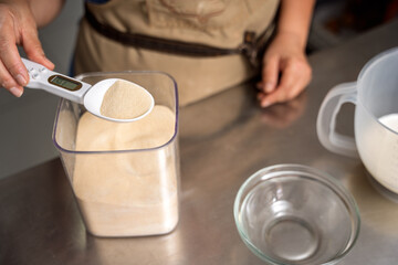 Pastry chef weighing yeast with digital spoon scale for baking