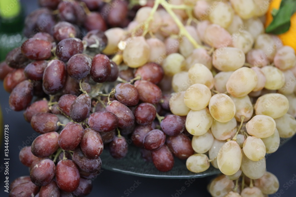 Aufkleber a cluster of red and green grapes sits atop a wooden or glass table surface.