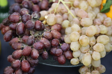 A cluster of red and green grapes sits atop a wooden or glass table surface.
