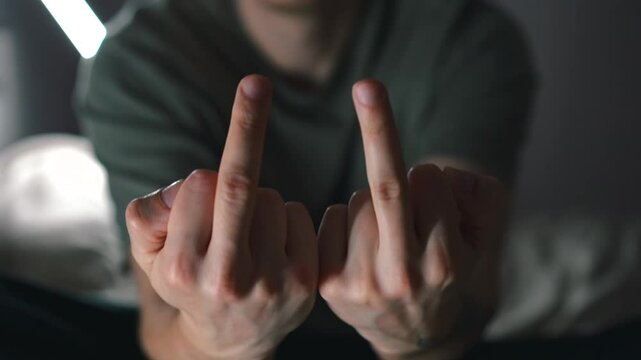 Man sits on sofa and shows average asshole to camera.
Evil man shows FUCK gesture to camera.
Obscene hand gesture