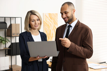 Coworkers with laptop working together in office