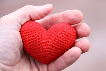 A person holding a handmade red crocheted heart, perfect for expressing love and affection.