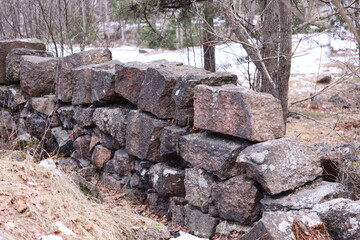A natural stone wall amidst dense foliage, suitable for outdoor scenery and environmental contexts.