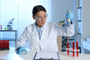 Laboratory testing. Doctor dripping blood sample into test tube at table indoors