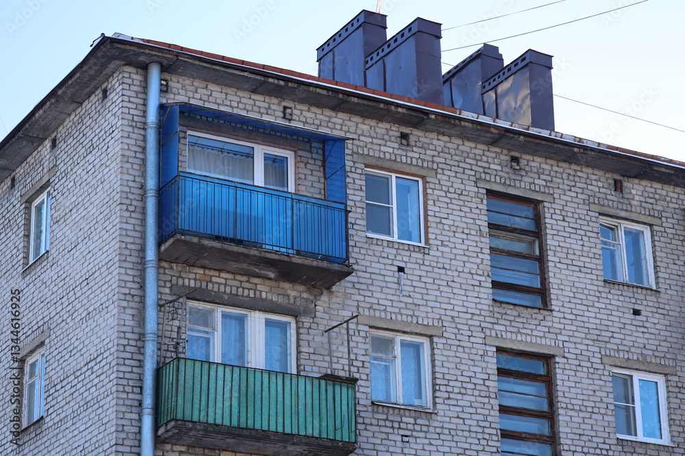 Poster a tall brick building with a blue balcony, suitable for use in architecture or urban design illustra