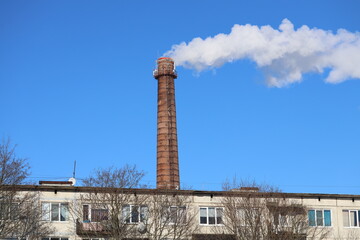 Fototapeta premium A smokestack emitting smoke from a chimney on the side of a building, great for use as a background or to illustrate industrial or urban themes.