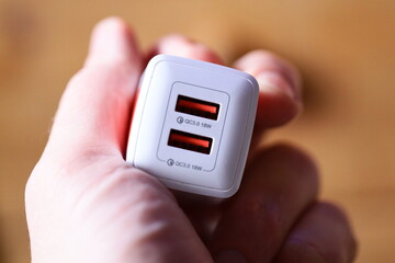 A person holds a small white device in their hand, possibly a phone or tablet.