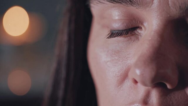 Close up of a woman meditating with closed eyes in soft candlelight, exuding calm and tranquility in a peaceful setting