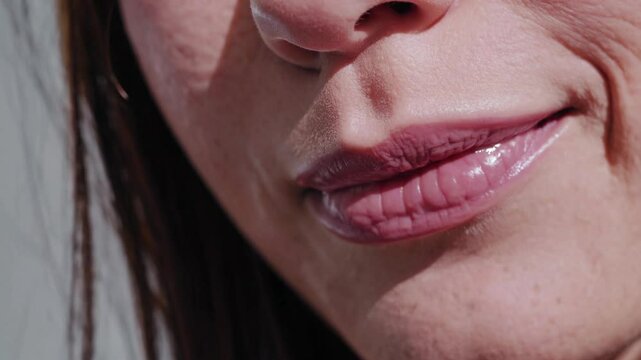 Detailed view of a woman's lips forming a playful smirk and subtle movements, showcasing expression and emotion through lip gestures