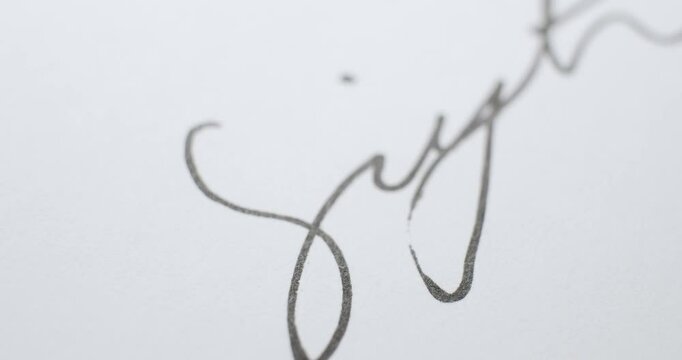 Signing a name on a contract with unique handwriting using a ballpoint pen in black ink. Close up of a cursive signature on paper using a ball point pen.