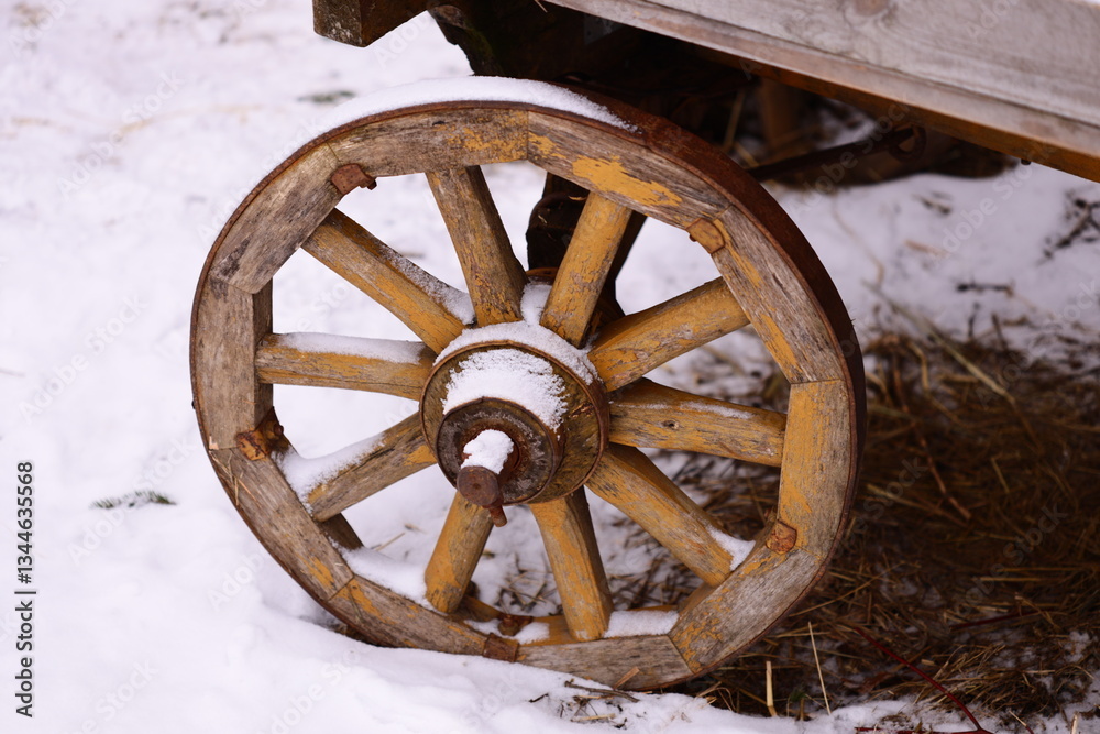 Poster a rustic wooden wagon wheel sits amidst winter snow, perfect for use as a decorative element or rust