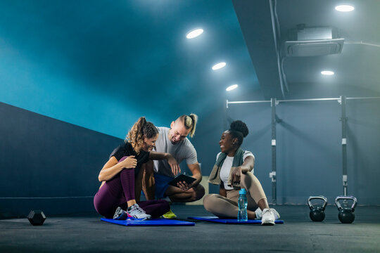 Personal trainer showing results to clients on tablet in gym