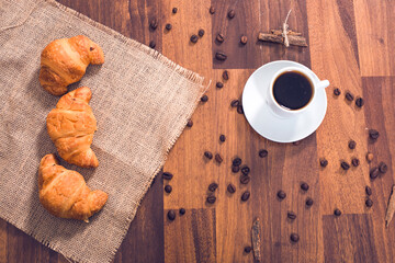 cup of coffee croissants and wall of wood