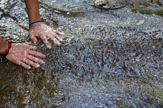 Female Hands submerged in flowing stream of water in Villeta, Cundinamarca, Colombia. Close-up interaction with nature highlighting sensory experience