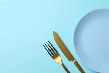 Blue empty plate with cutlery on a colored background