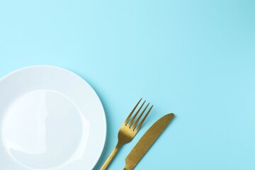White empty plate with cutlery on a colored background