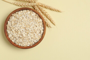 Composition with oatmeal flakes on beige background. Cooking breakfast