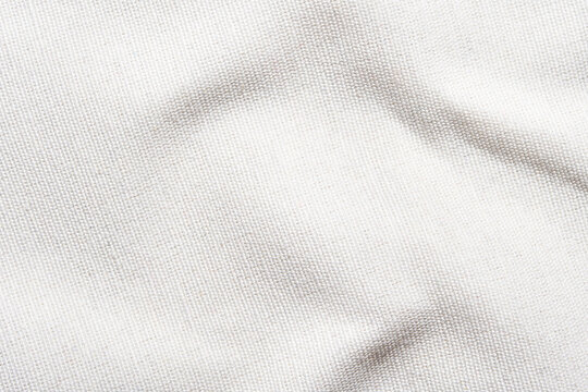 Close-up of textured white fabric with natural light and soft shadows.