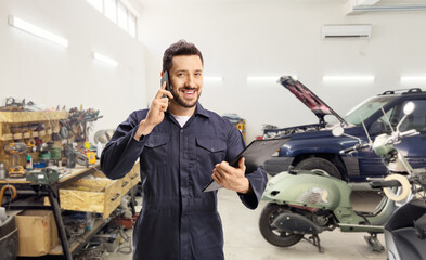 Male worker in a blue uniform using a smartphone at a car garage