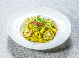 homemade pesto sauce pasta with shrimp, pesto sauce, and fresh herbs served on a wooden board side view of hong kong food on a textured stone background