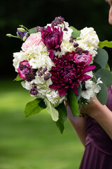 A vibrant wedding bouquet with rich burgundy, pink, and white flowers