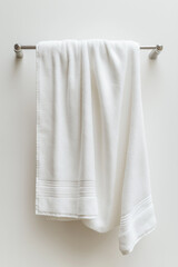 A pristine white bath towel draped over a sleek, silver towel bar against a minimalist white wall. Soft texture and clean lines.