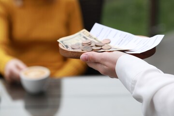 Fototapeta premium Waitress holding tips, receipt and payment for order in outdoor cafe, closeup
