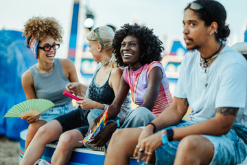 Young friends enjoying music festival together sitting and laughing