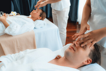 Fototapeta premium Caucasian couple enjoying relaxing anti-stress head massage and pampering facial beauty skin recreation leisure in dayspa modern light ambient at luxury resort or hotel spa salon. Quiescent