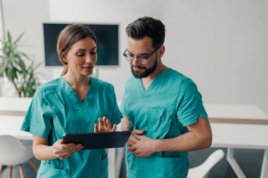 Two doctors using tablet, discussing patient's medical history in hospital room
