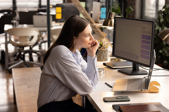 Focused woman working on computer at modern office, analyzing data