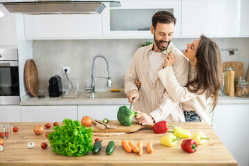 A joyful couple enjoys cooking in their modern kitchen, bonding over fresh vegetables and creating delightful meals together.