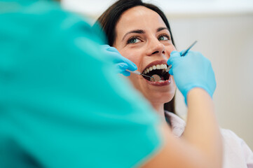 Dentist examining patient's teeth with dental tools during check up