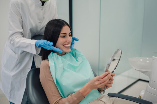 Happy patient admiring her perfect smile after dental treatment