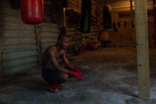 Boxer resting in rustic gym, wearing red gloves, preparing for training, copy space