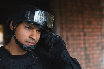 Tactical officer in black gear communicating through earpiece, focused on mission, copy space