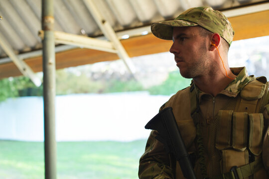Military man in camouflage holding rifle, focused and alert during training exercise, copy space