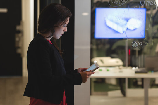 In modern office, businesswoman concentrating on work while using smartphone, copy space