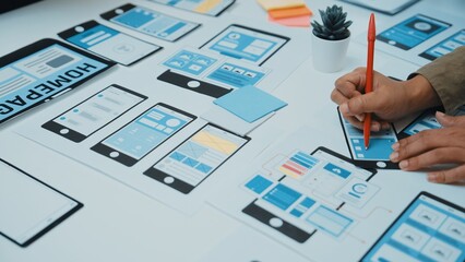A professional is actively designing a user interface wireframe with paper prototypes in a modern...