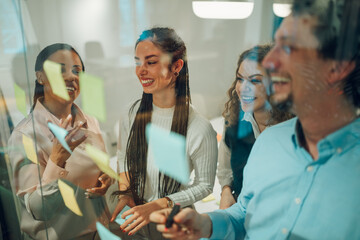 Businesspeople using sticky notes during brainstorming session in office