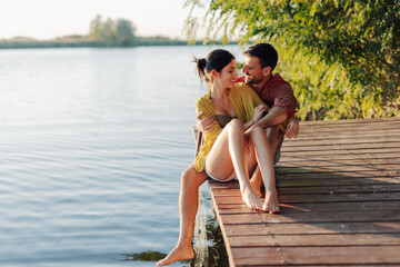 Fototapeta premium Happy couple relaxing and enjoying a romantic sunset on a lake pier