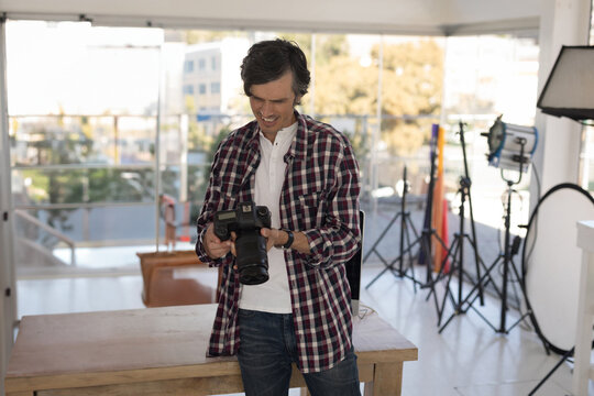 Photographer reviewing camera settings in bright studio, preparing for photoshoot