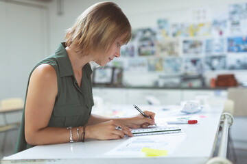 Designer sketching architectural plans with ruler and pencil in creative studio, copy space