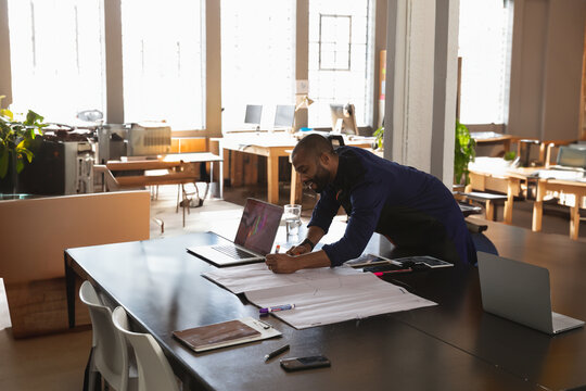 Designer sketching on paper at modern office desk with laptop and tablet, copy space