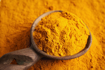 Dry turmeric root powder on a spoon