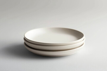 Minimalist design highlights three elegant white plates stacked quietly on a textured surface, evoking simplicity and sophistication in contemporary dining