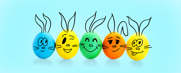 Bright Easter eggs with bunny ears and faces on light blue background, banner design