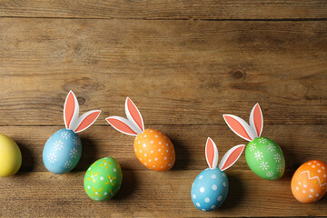Bright Easter eggs on wooden table, top view. Some of them with bunny ears