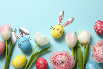 Bright Easter eggs and flowers on light blue background, top view. Some of them with bunny ears, noses and whiskers