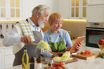 Senior couple using tablet while cooking together in kitchen